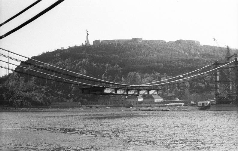 az épülő Erzsébet híd és a Gellért-hegy a pesti alsó rakpartról nézve.